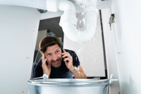 Man looking at a leaking sink pipe